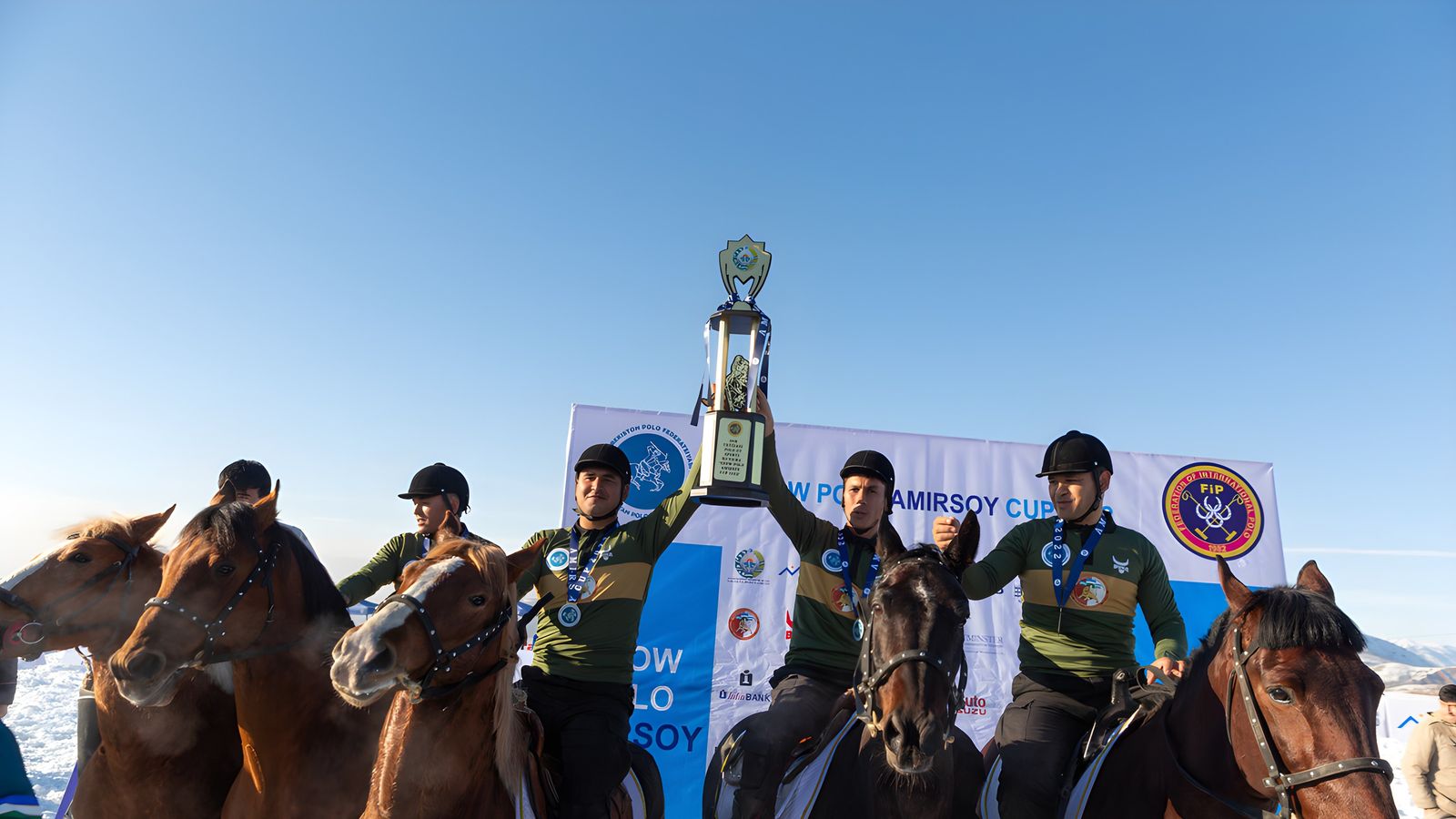 A team on horseback raises a trophy under a blue sky